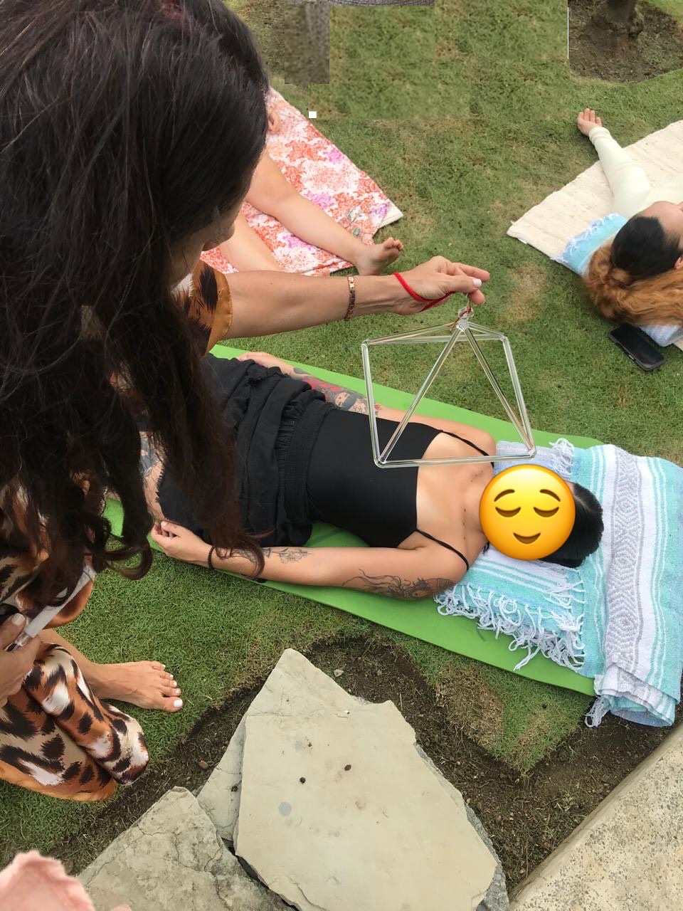 Liu estructurando la energía de una participante con una pirámide de cristal en la grama